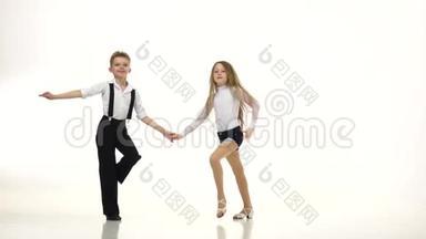 穿着漂亮服装的小舞者表演一支舞蹈。 白色背景。 缓慢的一元